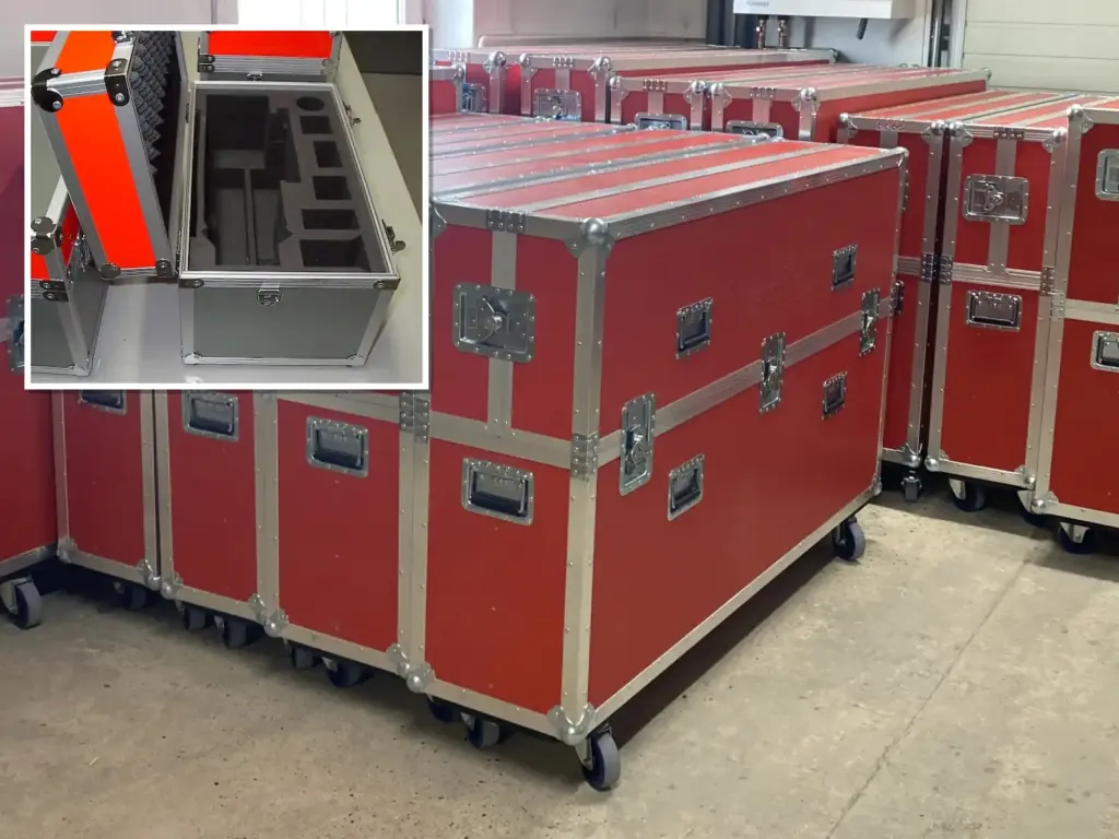Große rote Flightcases auf Rollen in der Fertigung, davor ein Alukoffer mit gefrästem Schaumstoff
